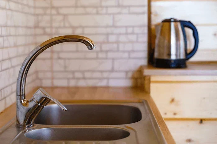 An image of a kitchen faucet running with a boil water advisory notice nearby.