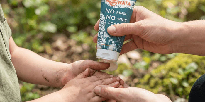 An image of a parent applying Nowata rinse-free soap to a child's dirty hands outdoors where Doctors created a plant-based, chemical-free soap that removes 99.9% of germs — no water or harsh ingredients needed.