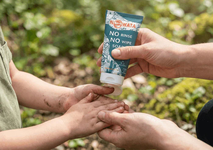 An image of a parent applying Nowata rinse-free soap to a child's dirty hands outdoors where Doctors created a plant-based, chemical-free soap that removes 99.9% of germs — no water or harsh ingredients needed.