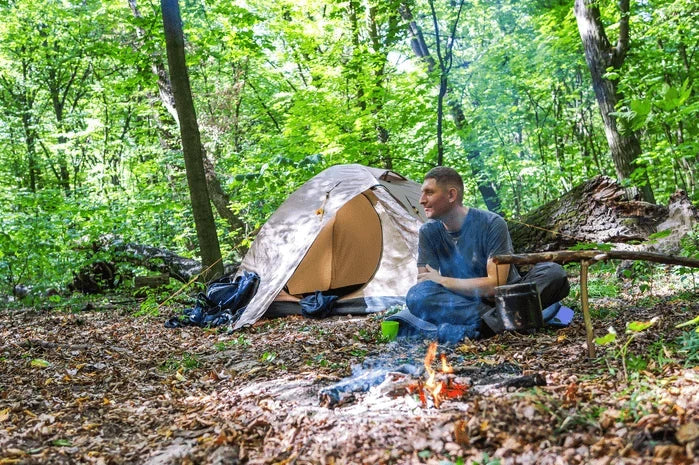 View of a hiker at a backcountry campsite beside a tent.