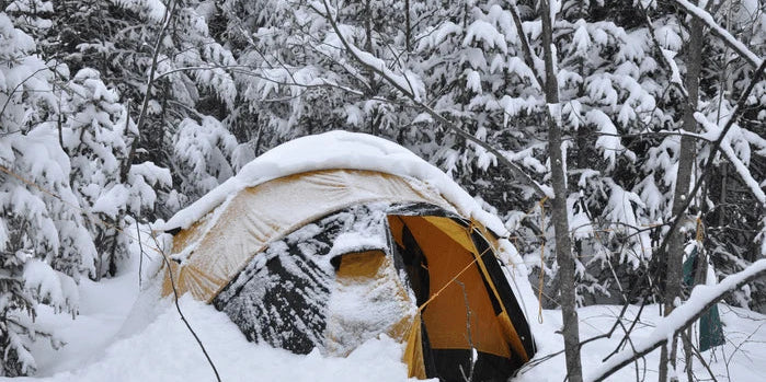 An image of a tent pitched in deep snow at a winter campsite.