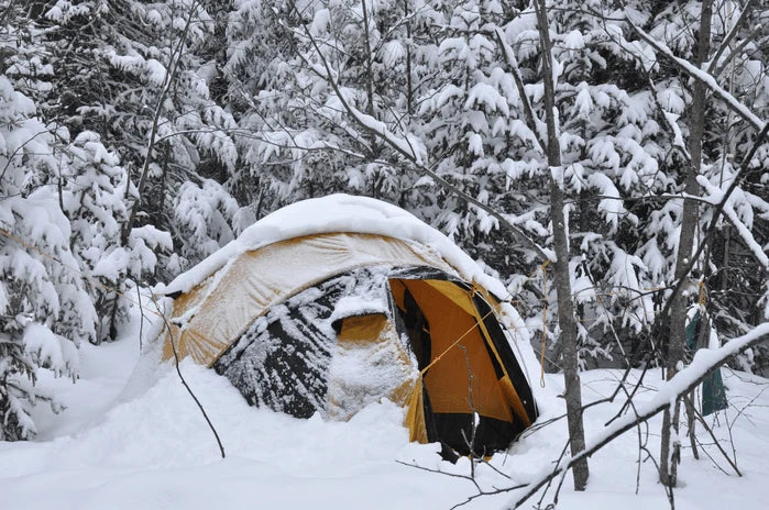 An image of a tent pitched in deep snow at a winter campsite.