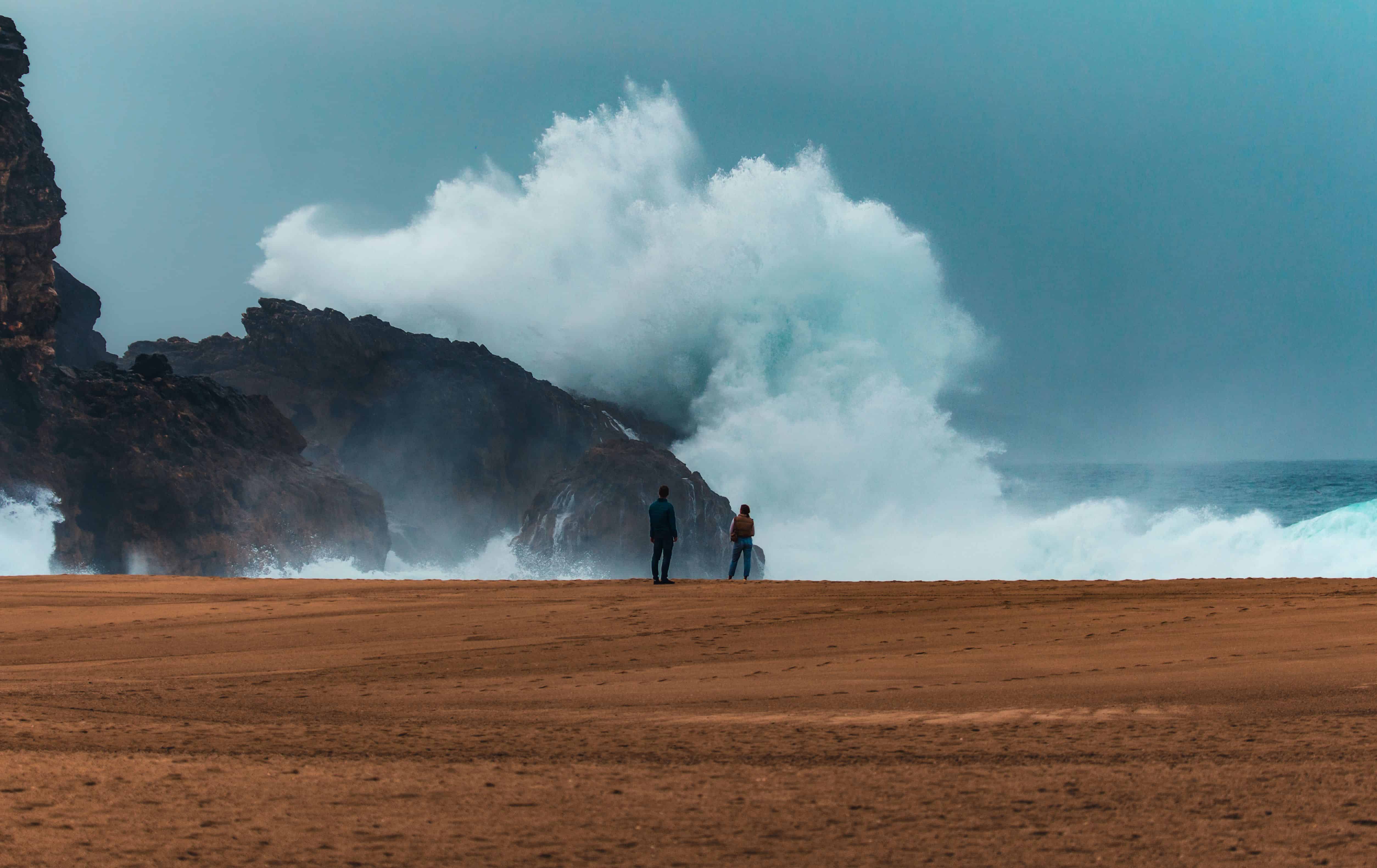 Big waves crashing into a rock with two observers