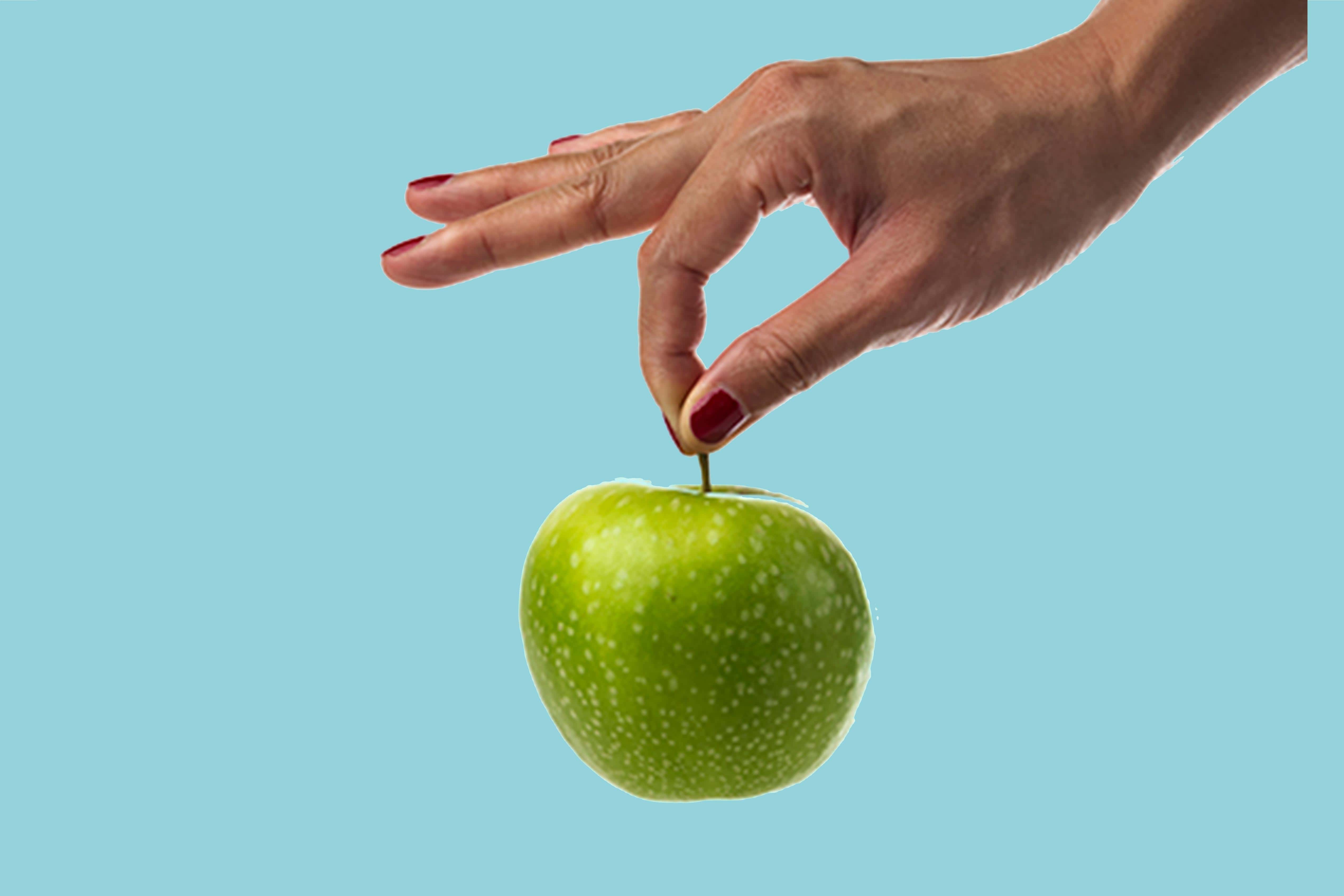 Hand holding apple. Malic acid is found in fruits like apples. Benefit: helps exfoliate and renew skin.