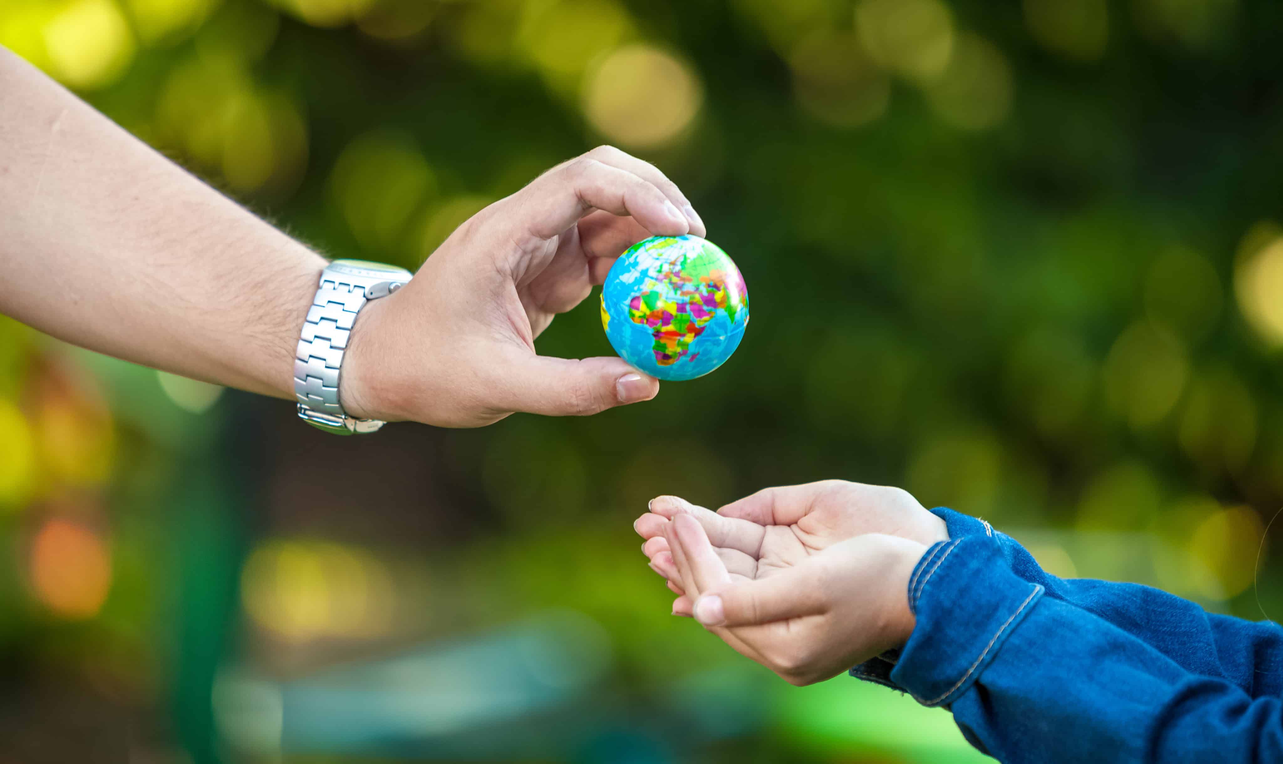 Man giving earth globe to little girl